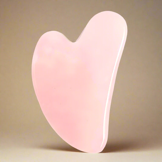 Pink gua sha tool on a white background